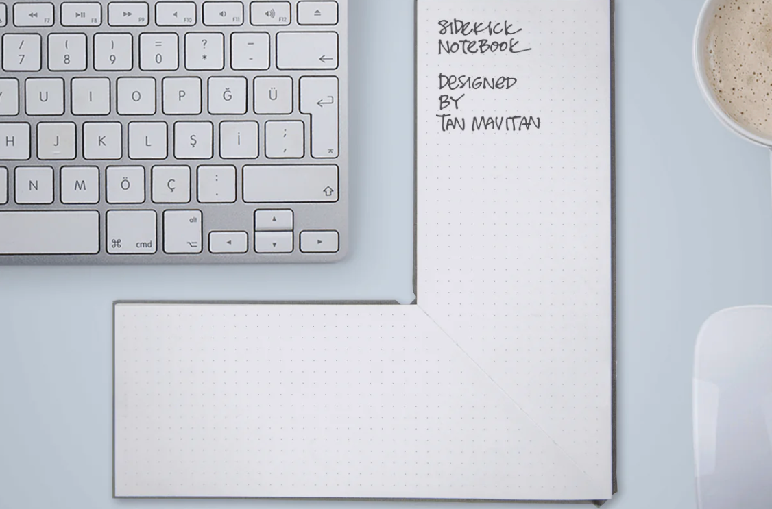 Keyboard with L-shaped notebook next to di and a pen below.